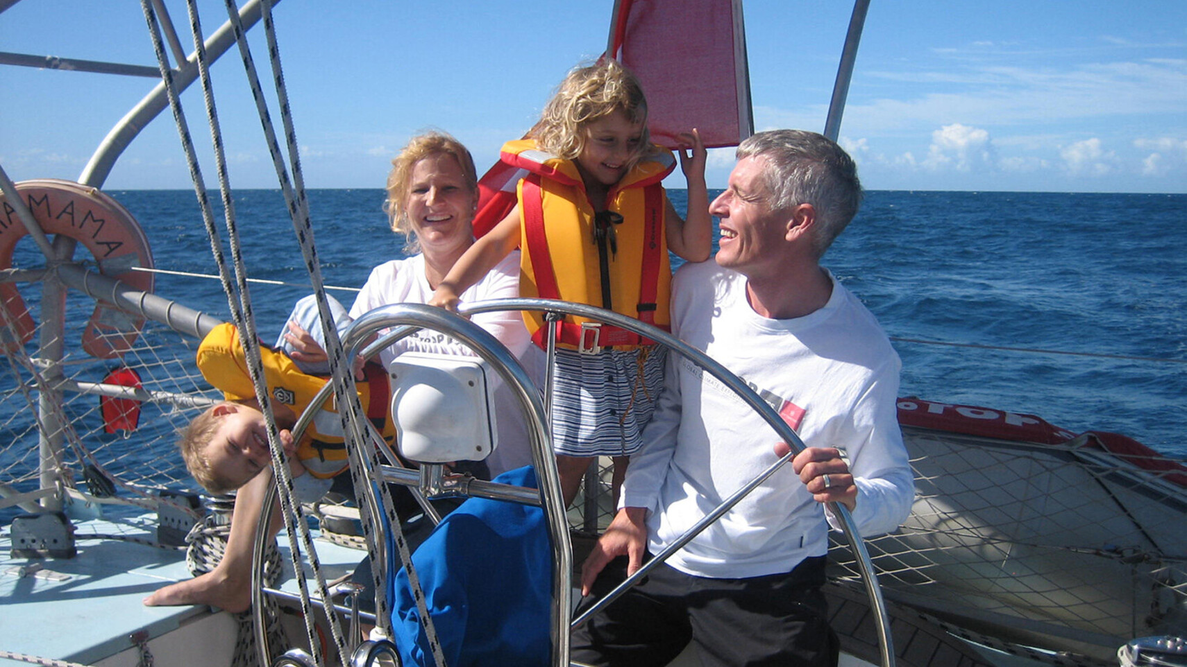 TOPtoTOP Expeditionsfamilie Schw&ouml;rer am Steuer ihres Segelbootes in tropischen Gew&auml;ssern bei Bundaberg, Australien &ndash; Kinder mit Schwimmwesten, sonnige Ozean&uuml;berquerung, 2009